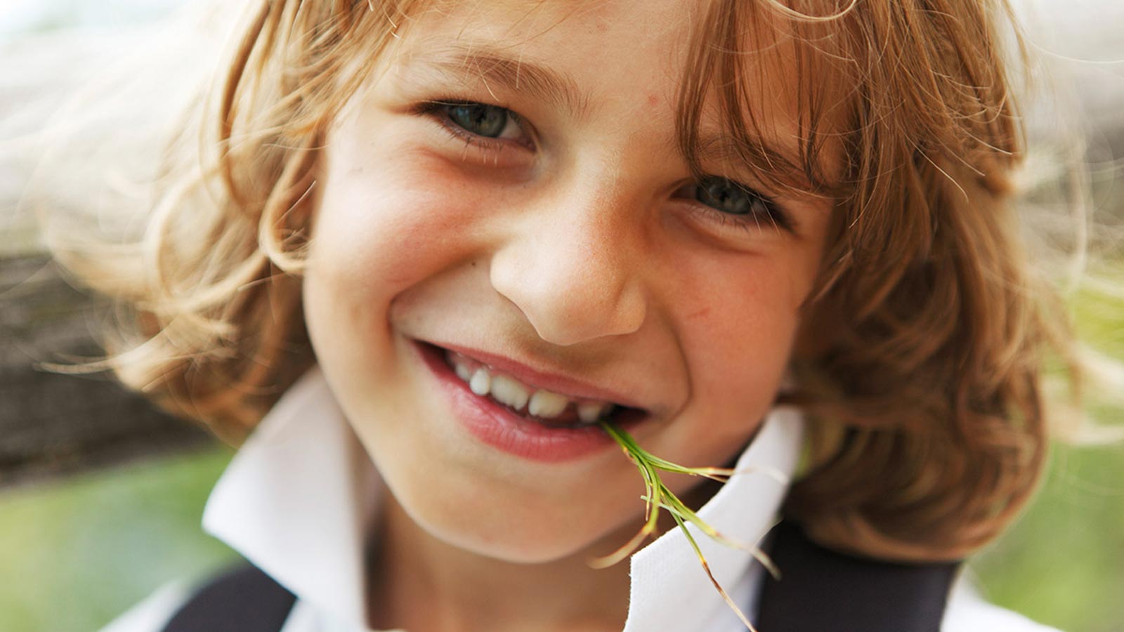 A child smiles with a sprig of rosemary in his mouth during a family holiday in South Tyrol