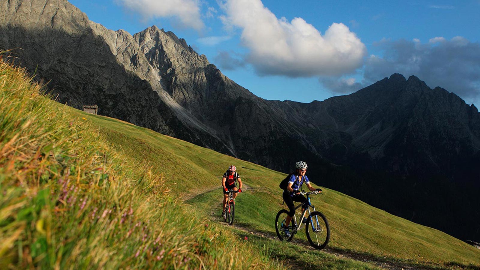 A couple enjoy mountain biking during a sunny day in the Dolomites