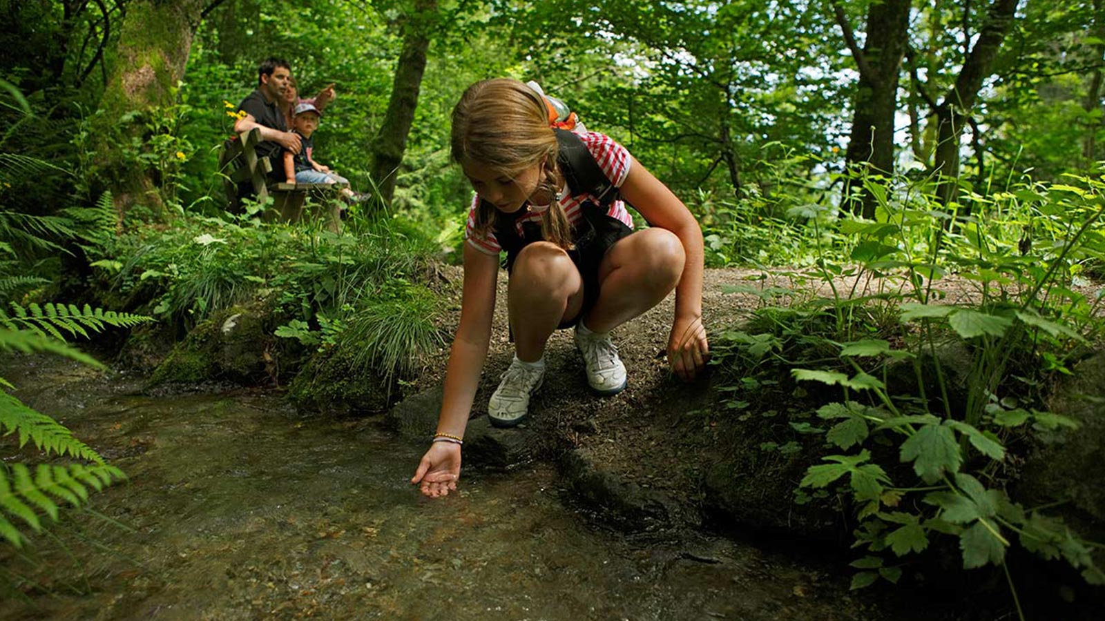 Ein kleines Mädchen spielt im Wald mit Wasser